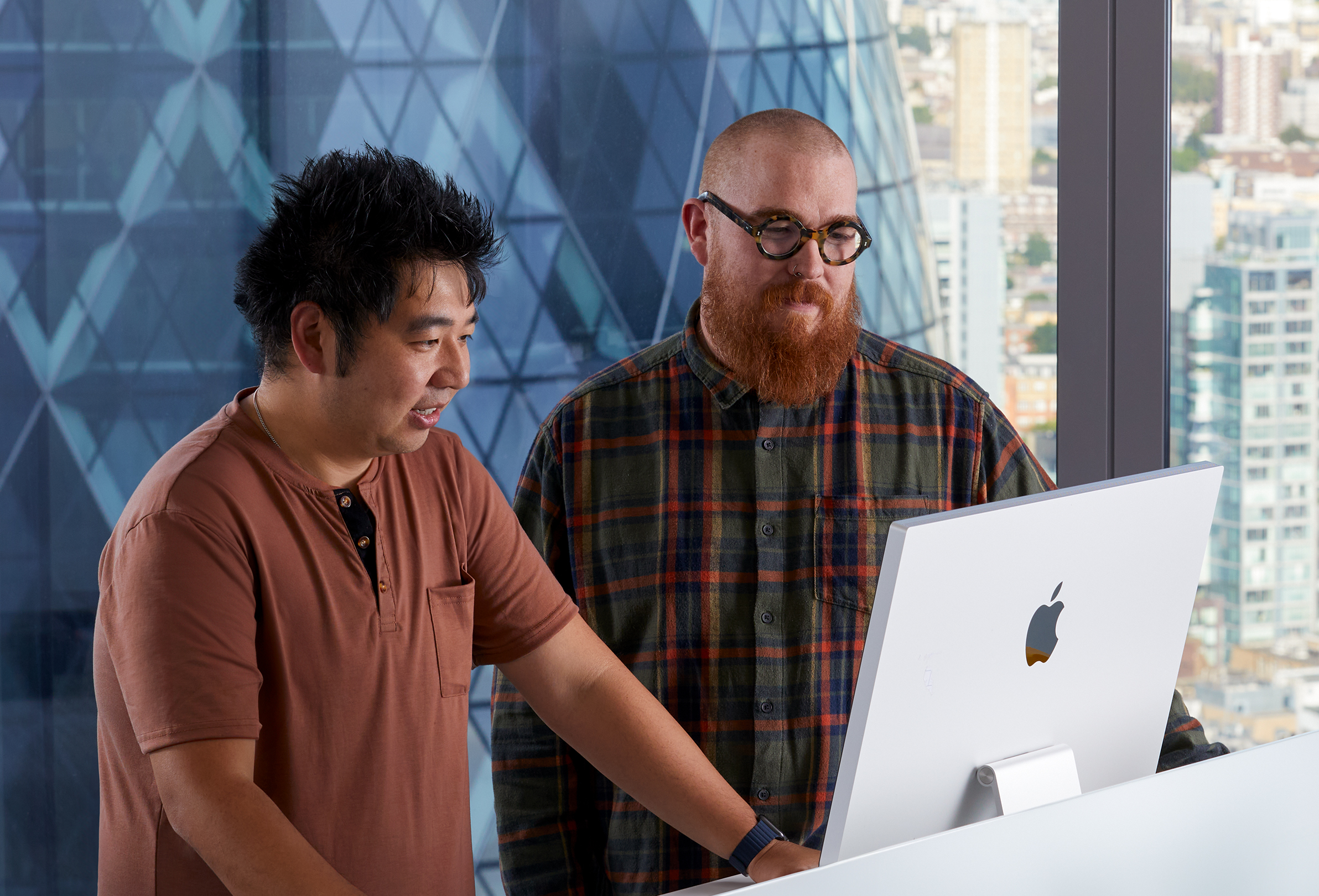 Dos colegas de Apple colaborando mientras usan una iMac.