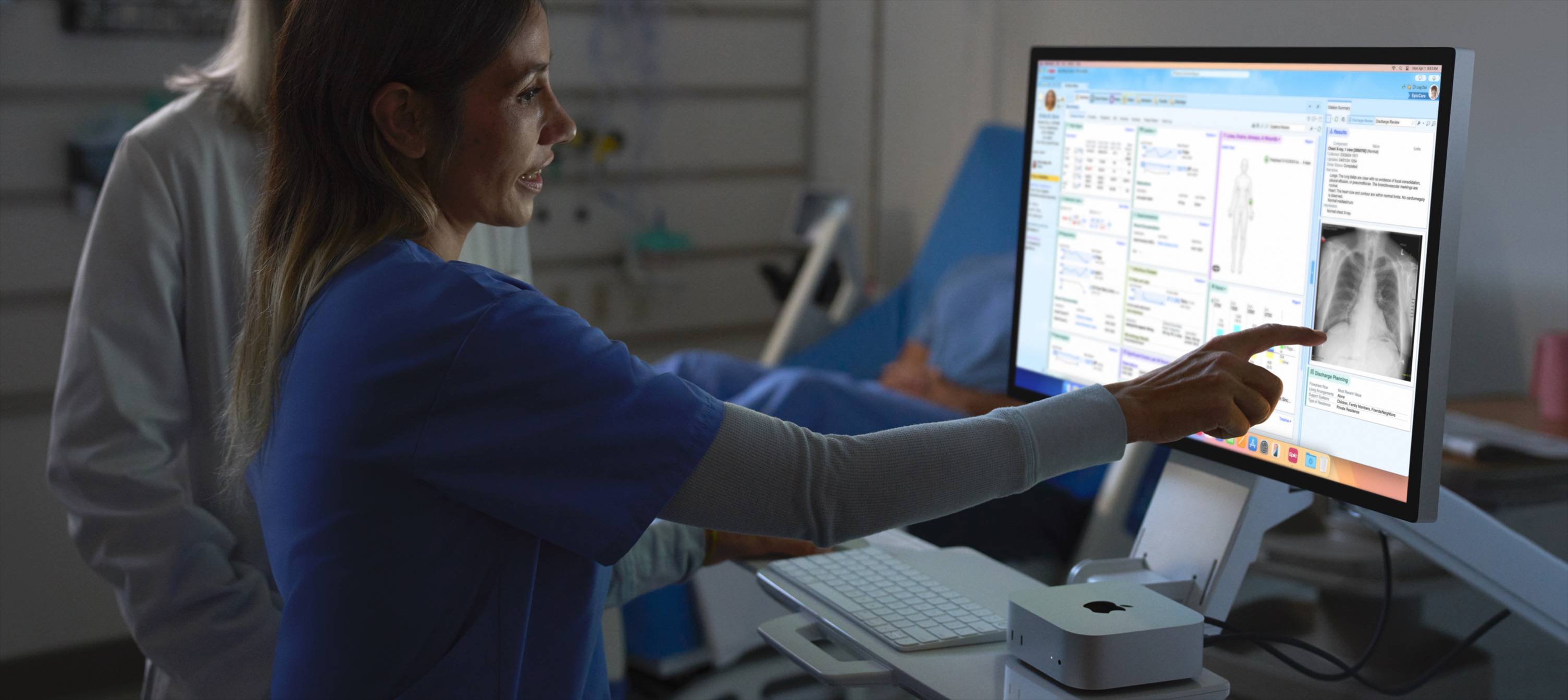 Et billede af en sygeplejerske, der peger på en patients røntgenbillede på en iMac.