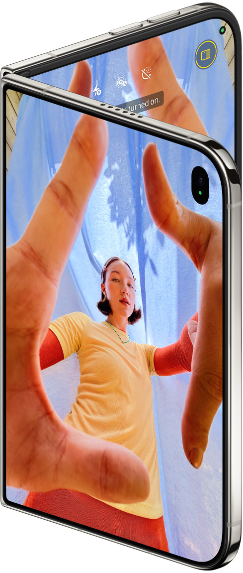 星光白色 iPhone Duo 微微打開，外螢幕展示 Center Stage 前置相機及相機 app，而內螢幕則顯示相機 app